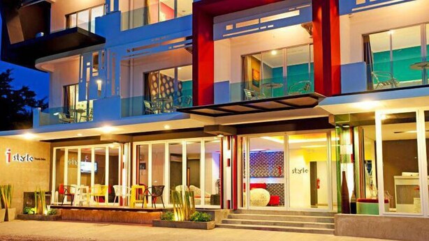 A modern hotel with a glass facade, outdoor seating, and a visible entrance. - I Style Hua Hin Hotel (Hua Hin)