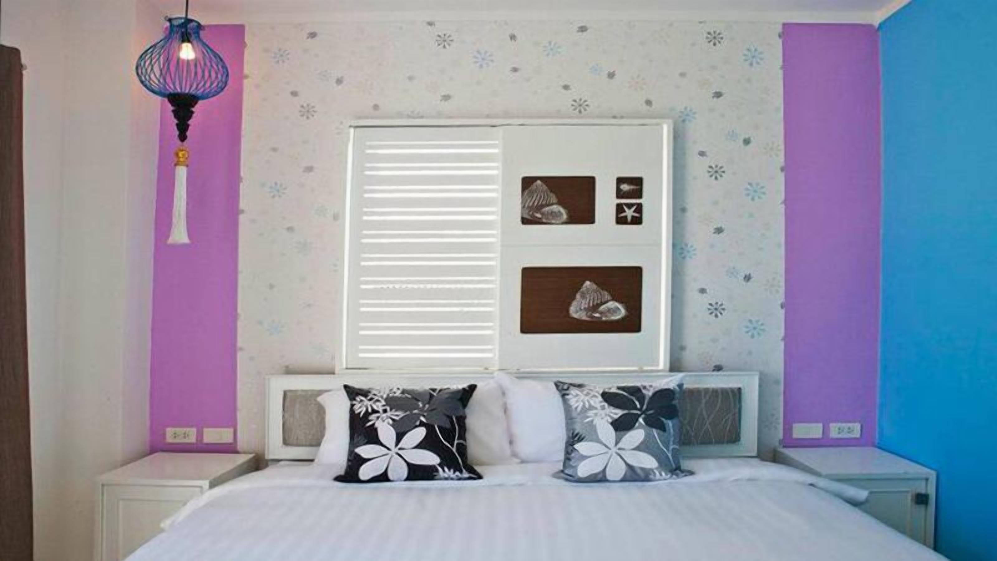 Una camera da letto con un letto, due cuscini, una finestra con persiane, decorazioni a parete e un lampadario.