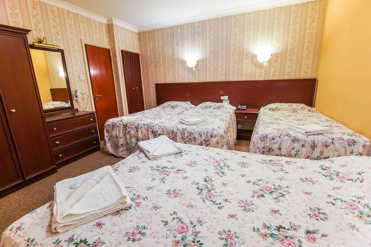 A hotel room with two beds, a dresser, a mirror, and a nightstand.