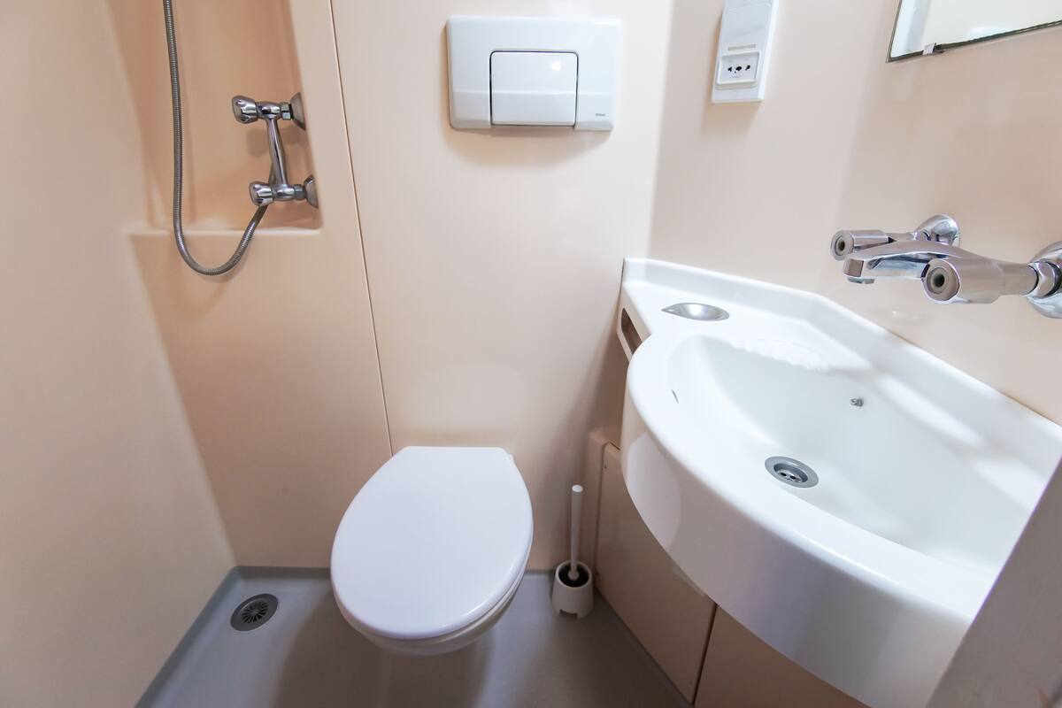 A small, modern bathroom with a white toilet, a shower, and a sink.