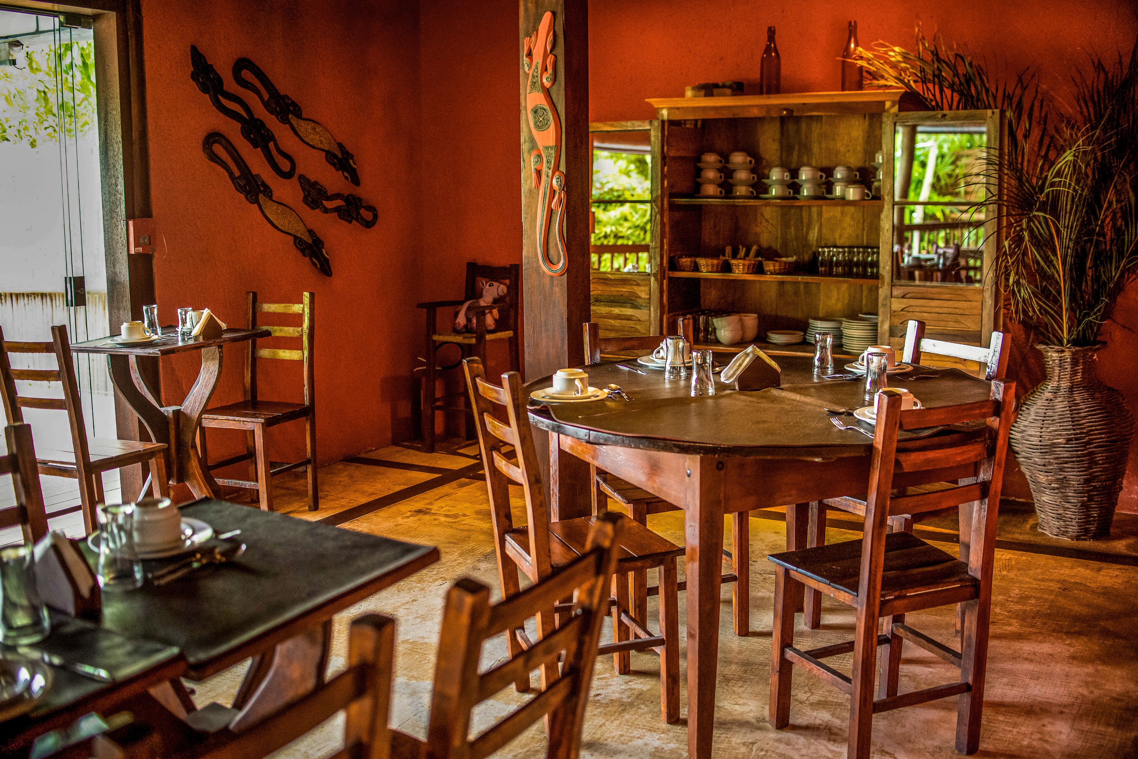 Un coin repas avec une table et des chaises en bois, une étagère contenant de la vaisselle et une décoration murale.