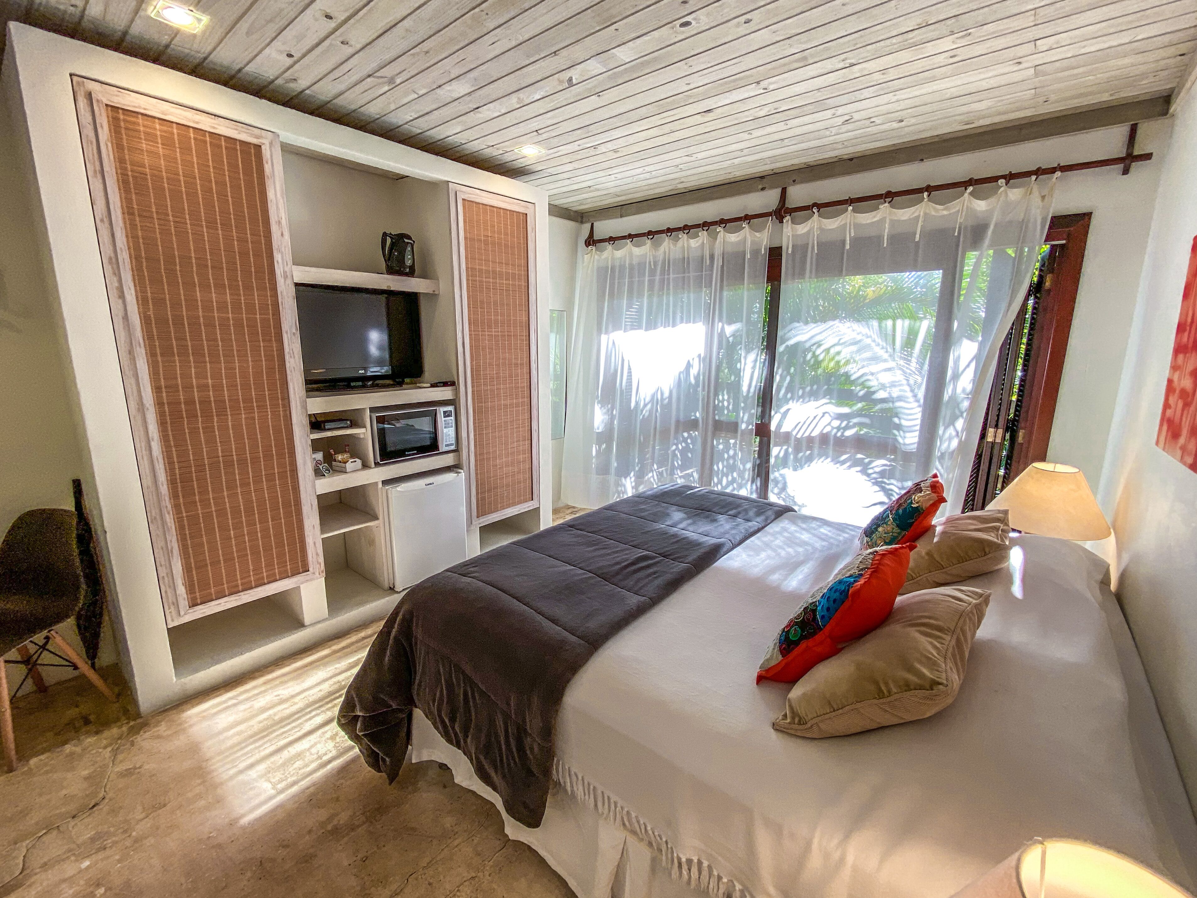 Un dormitorio con cama, televisor, refrigerador pequeño y armario.