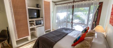 Un dormitorio con cama, televisor, refrigerador pequeño y armario.