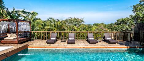 A swimming pool with lounge chairs and a wooden deck.