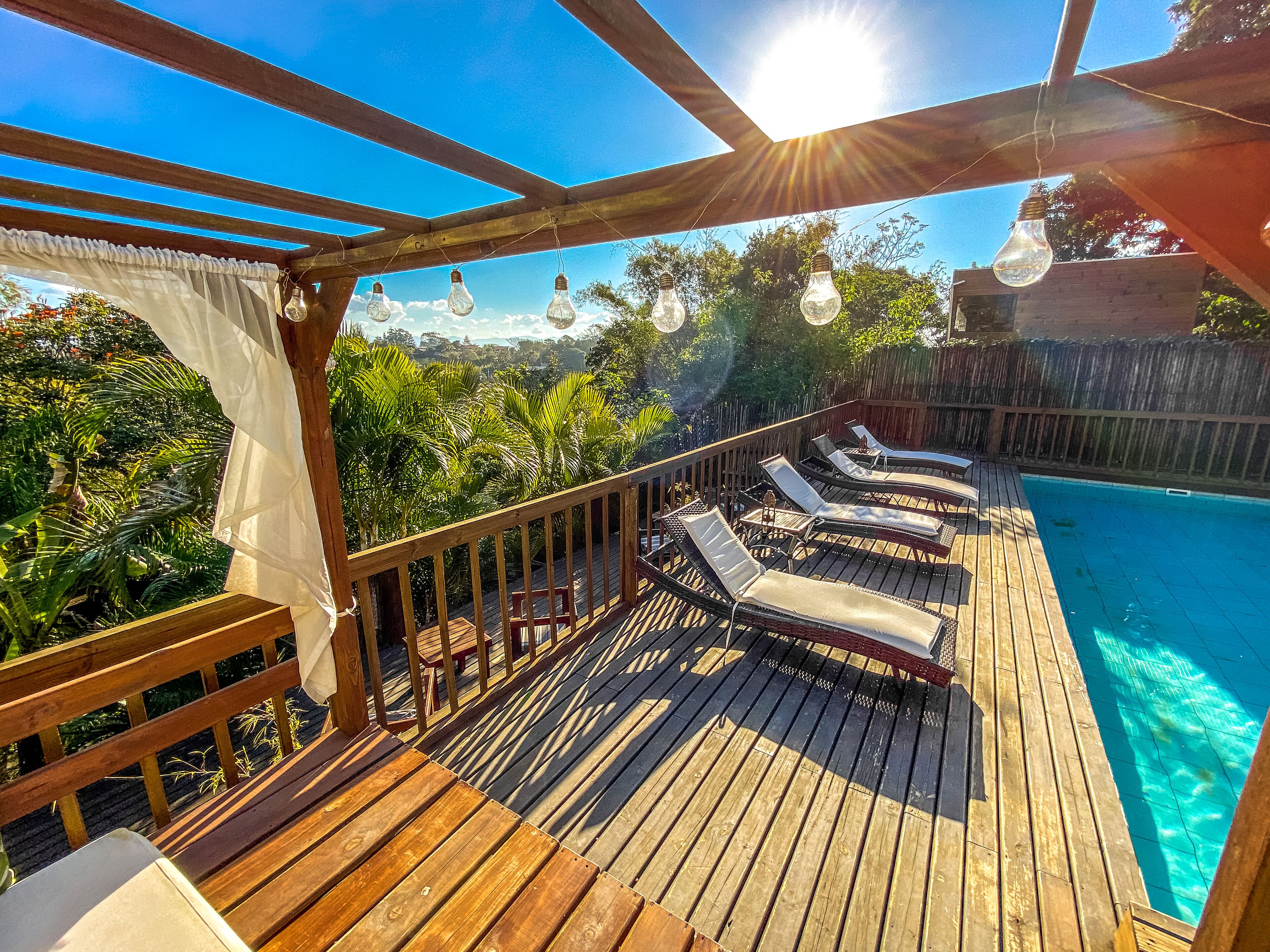 A wooden deck with lounge chairs and a pool.