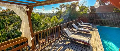 A wooden deck with lounge chairs and a pool.
