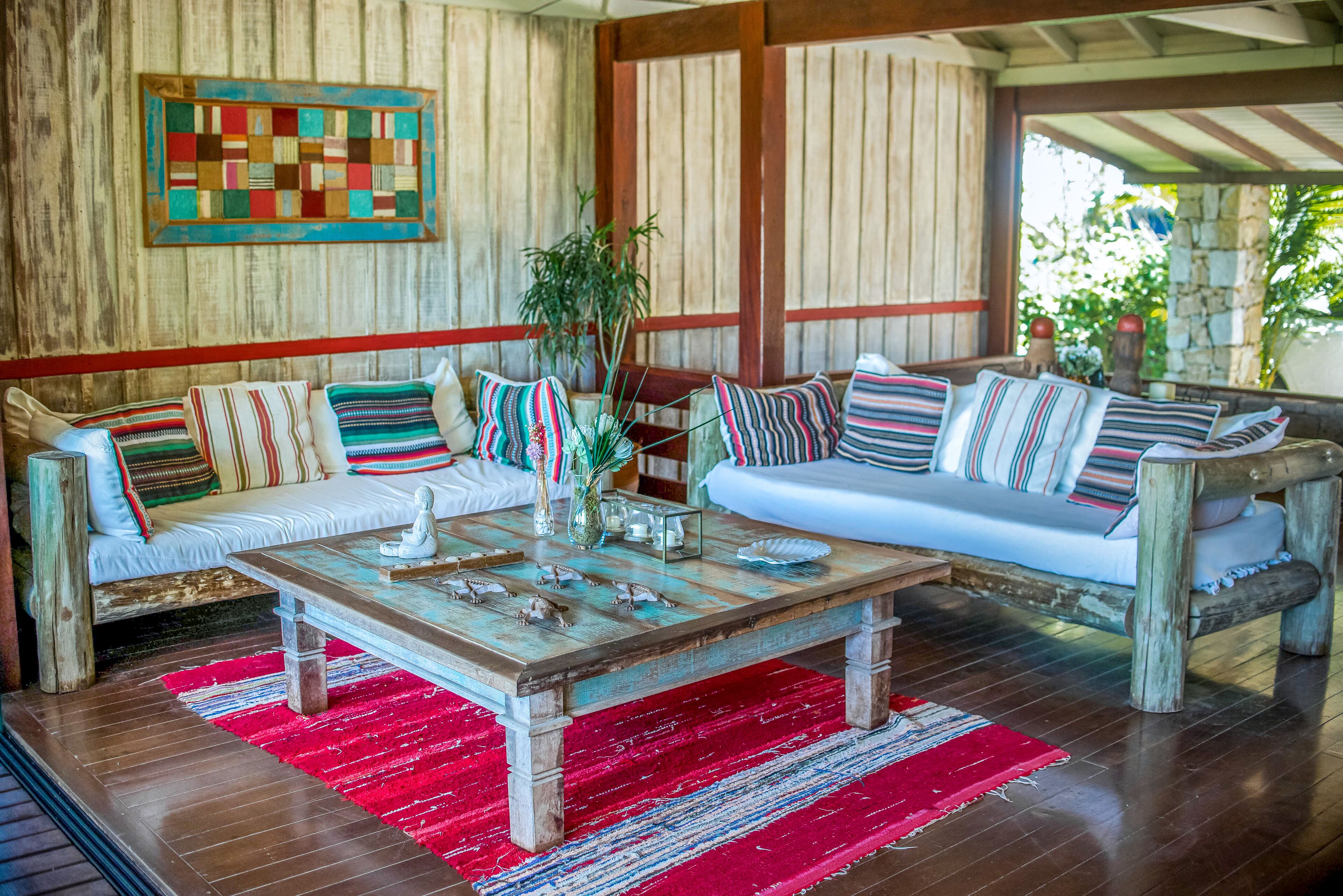 Una sala de estar acogedora con una mesa de centro de madera, cojines a rayas y una alfombra roja.