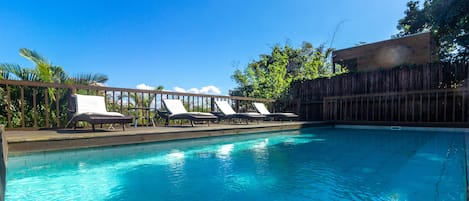 Relax by the serene pool surrounded by lounge chairs and lush greenery.
