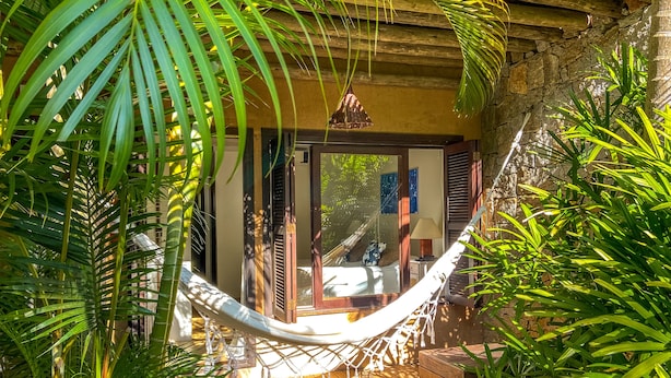 A hammock under a wooden pergola surrounded by lush green foliage. - Pousada Morada da Praia do Rosa (Imbituba)