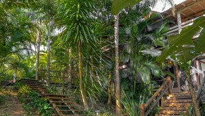 A wooden staircase surrounded by lush greenery and a rustic building structure. - Pousada Morada da Praia do Rosa (Imbituba)