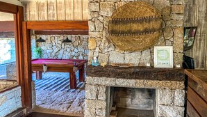 A stone fireplace with a framed certificate, a pool table, and a Buddha statue. - Pousada Morada da Praia do Rosa (Imbituba)