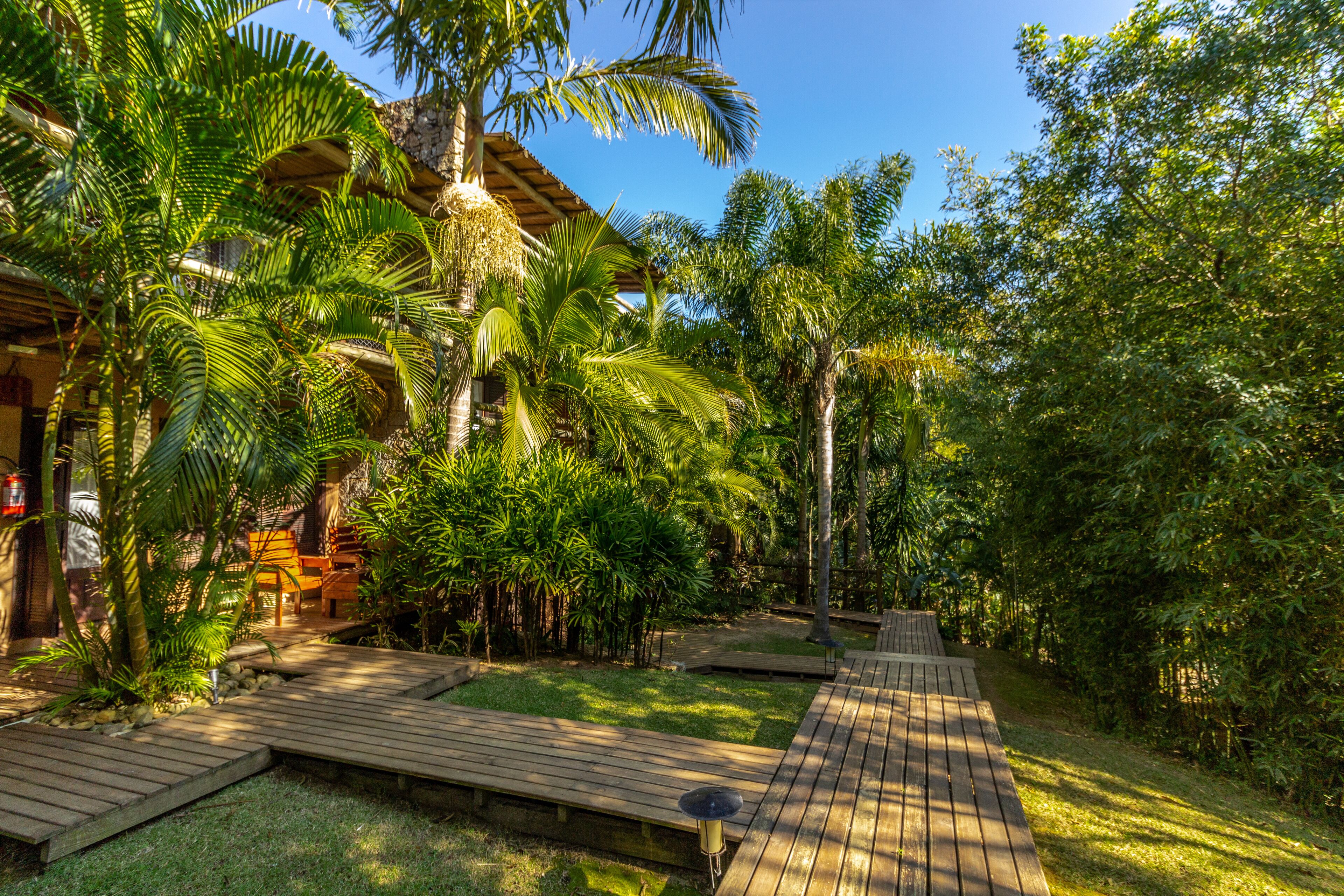 Un resort tropical con senderos de madera, palmeras y un edificio con techo de paja.