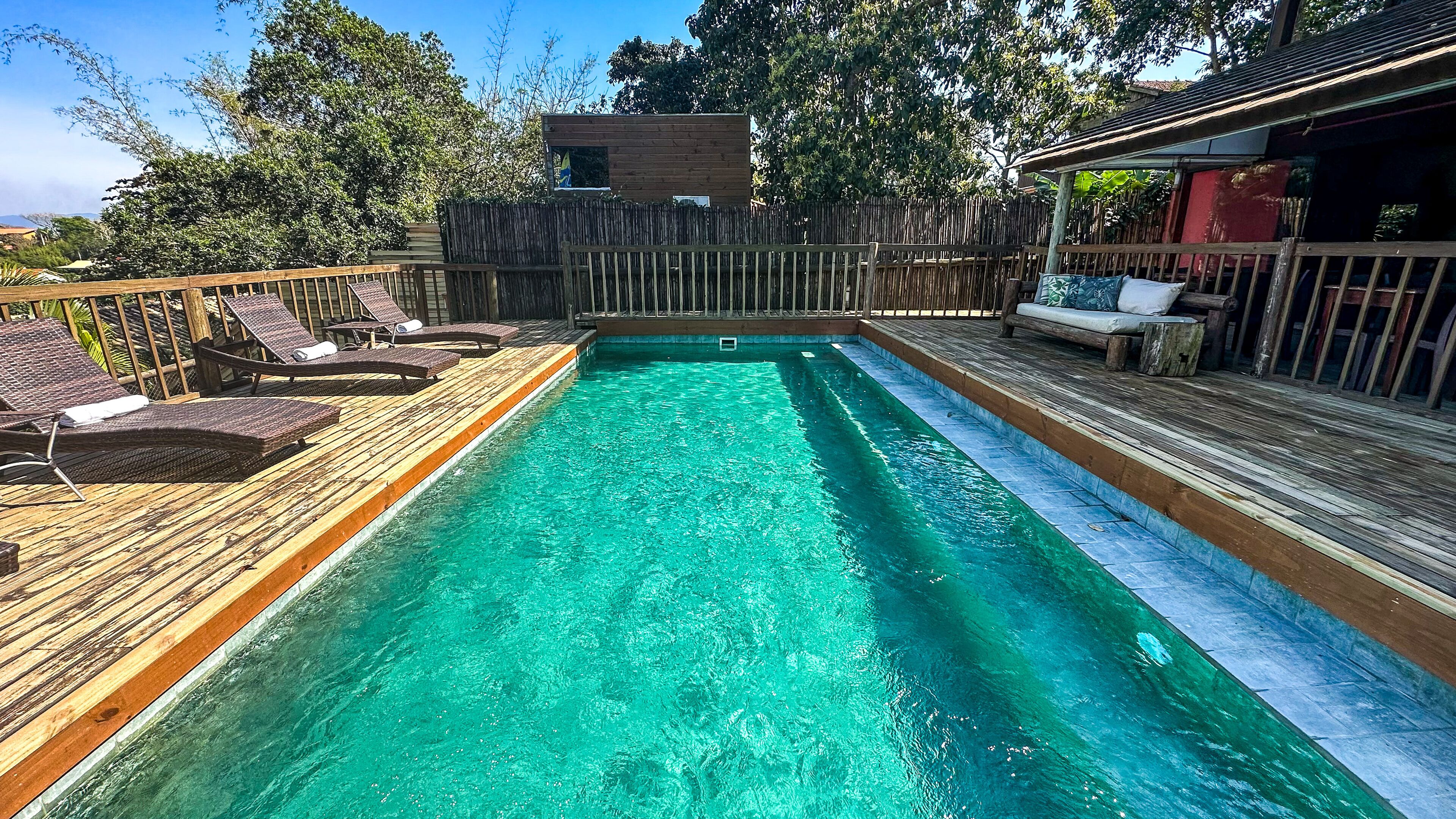 Una piscina con terraza de madera y sillas de descanso.