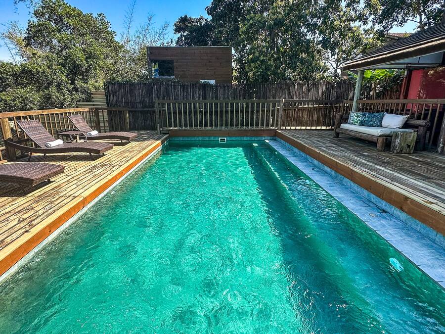 Una piscina con terraza de madera y sillas de descanso.
