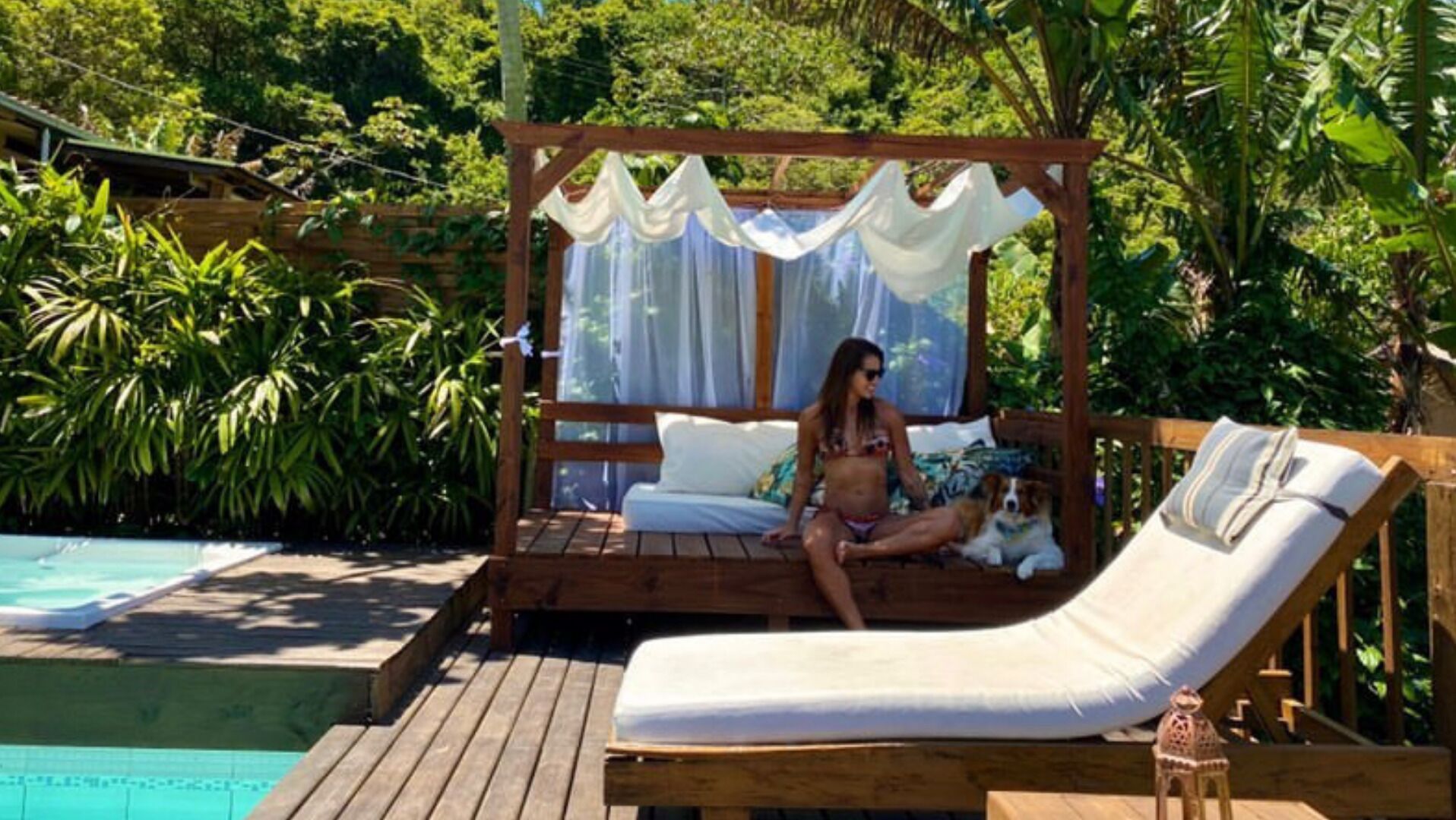 Une terrasse en bois avec un auvent, une piscine et un fauteuil de relaxation.