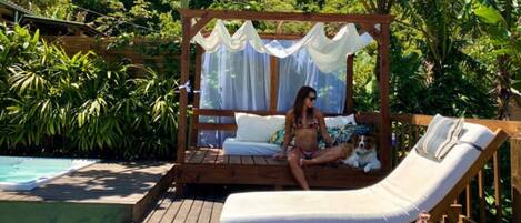 Une terrasse en bois avec un auvent, une piscine et un fauteuil de relaxation.