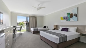 Habitación de hotel con dos camas, un escritorio y un balcón.