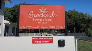 Un gran cartel de Beachside Boutique Motel Mackay con un número de teléfono de contacto.