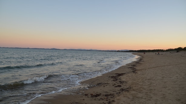 Una playa con arena y agua tranquila.