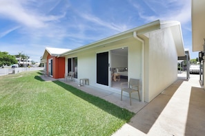 A modern house with a patio, sliding glass doors, and a well-maintained lawn. - Beachside Boutique Motel Mackay (East Mackay)