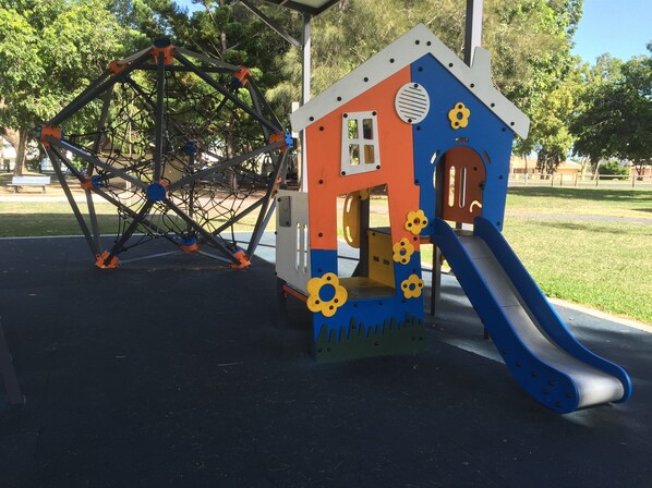 A playground with a Ferris wheel and a playhouse with a slide. - Beachside Boutique Motel Mackay (East Mackay)