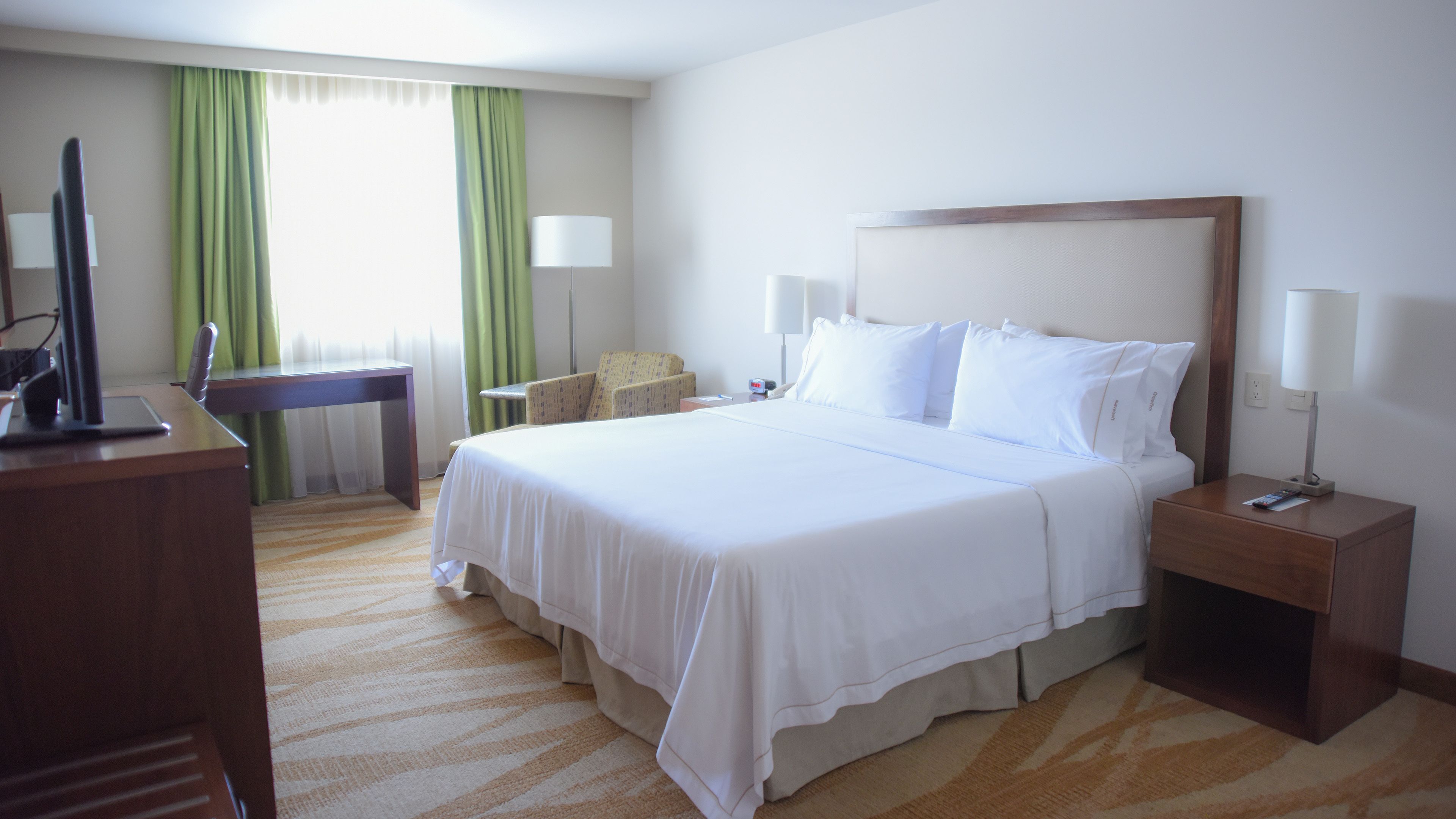 Una habitación de hotel con una cama grande, un escritorio, una silla y un televisor.