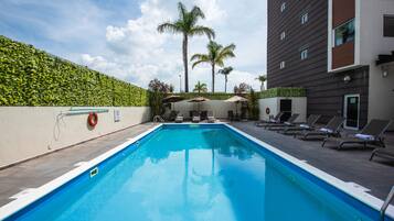 Relax by the pool surrounded by lush greenery and lounge under the shade of umbrellas.