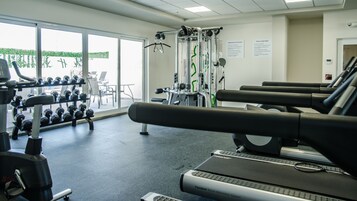 A gym with exercise equipment, including treadmills and dumbbells.