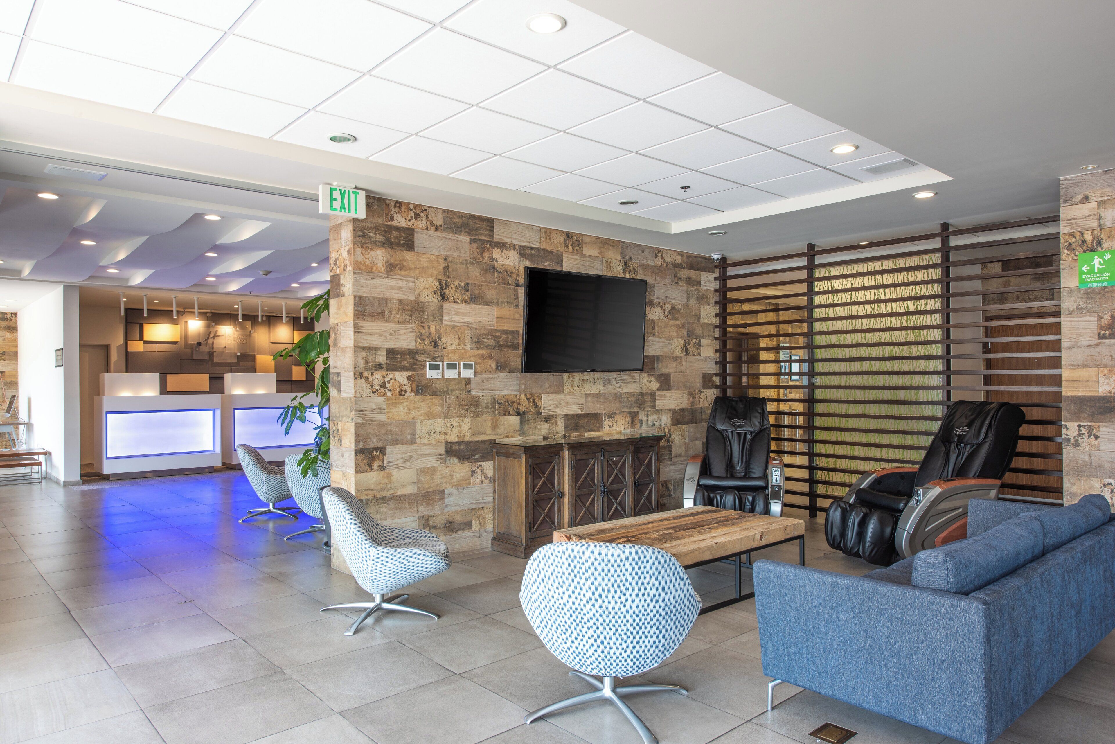 Un lobby moderno con un mostrador de recepción, área de descanso y una pantalla grande.