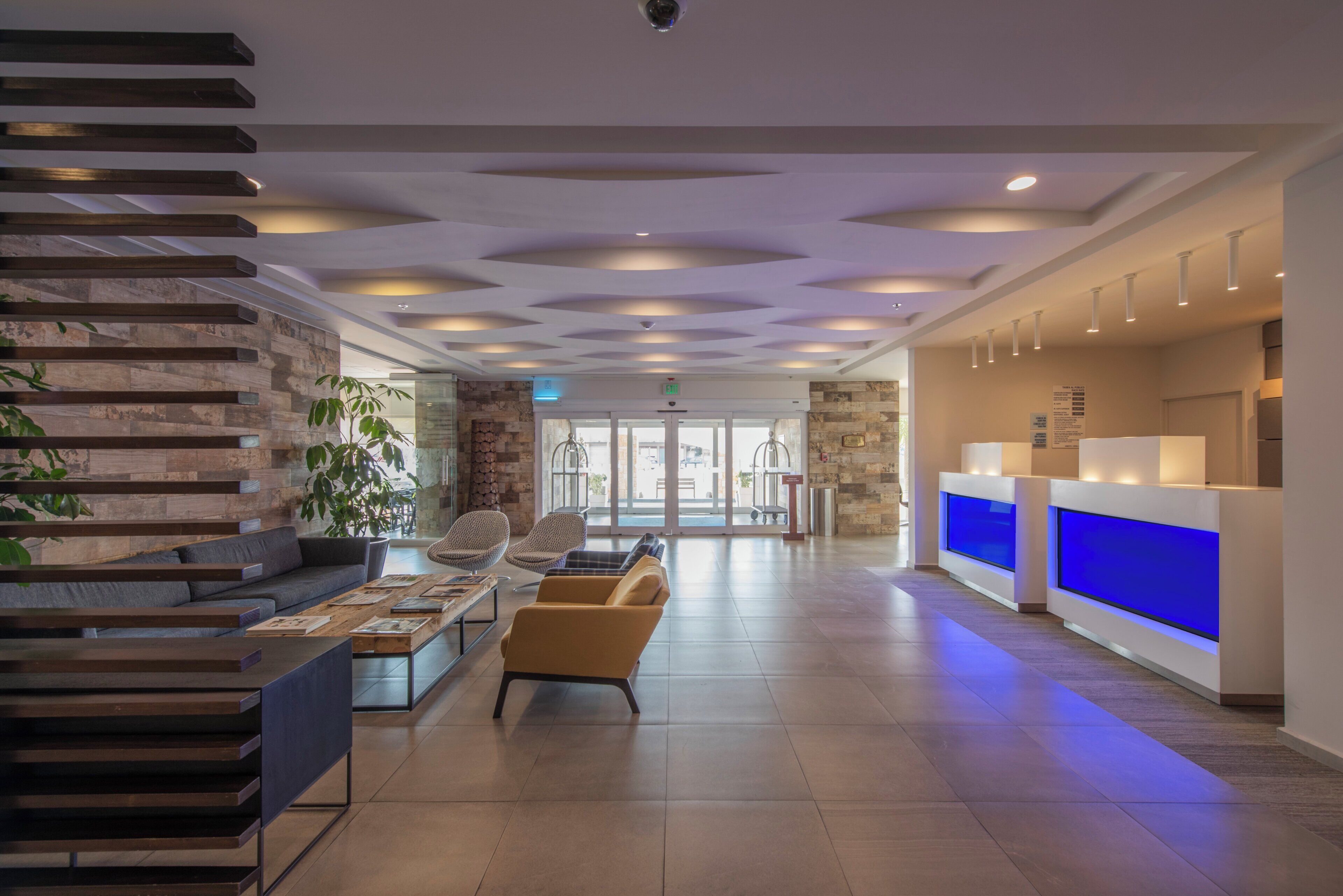 Un vestíbulo moderno con una mesa de recepción, zona de estar y una escalera.