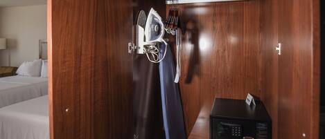 A wooden wardrobe with a built-in ironing station, including an iron and ironing board.