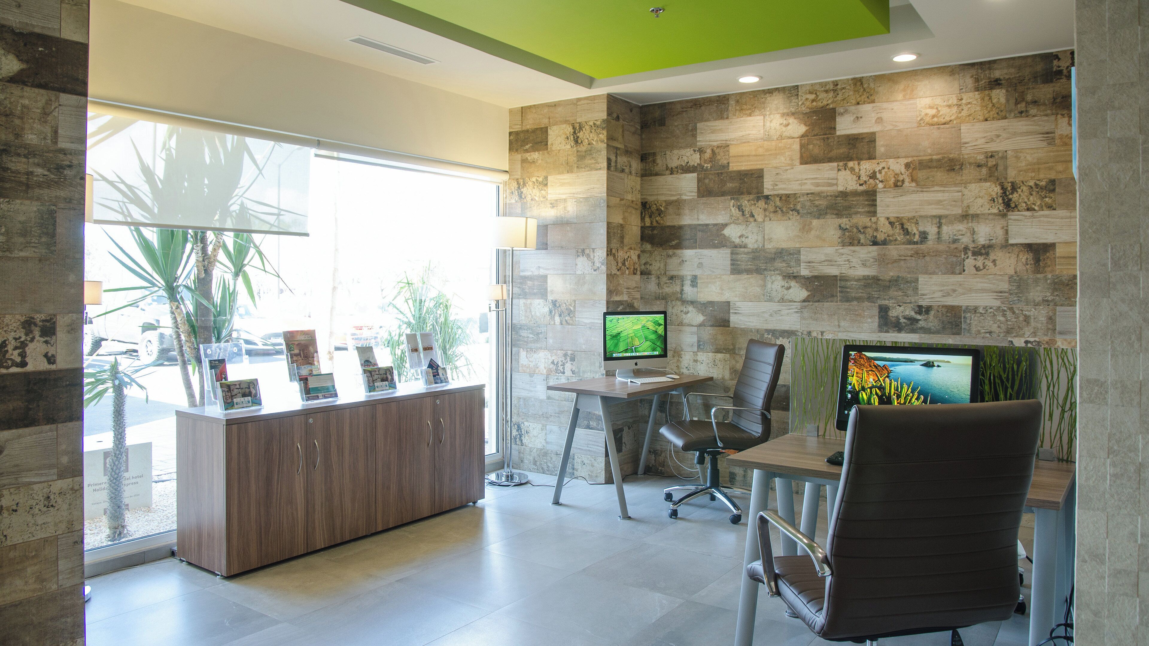 Zona de recepción con un escritorio de madera, dos monitores y sillas de oficina.