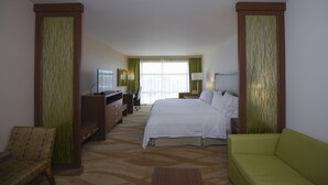 A hotel room with a bed, a desk with a TV, a chair, a green sofa, and a window with curtains. - Holiday Inn Express & Suites Celaya by IHG (Celaya)
