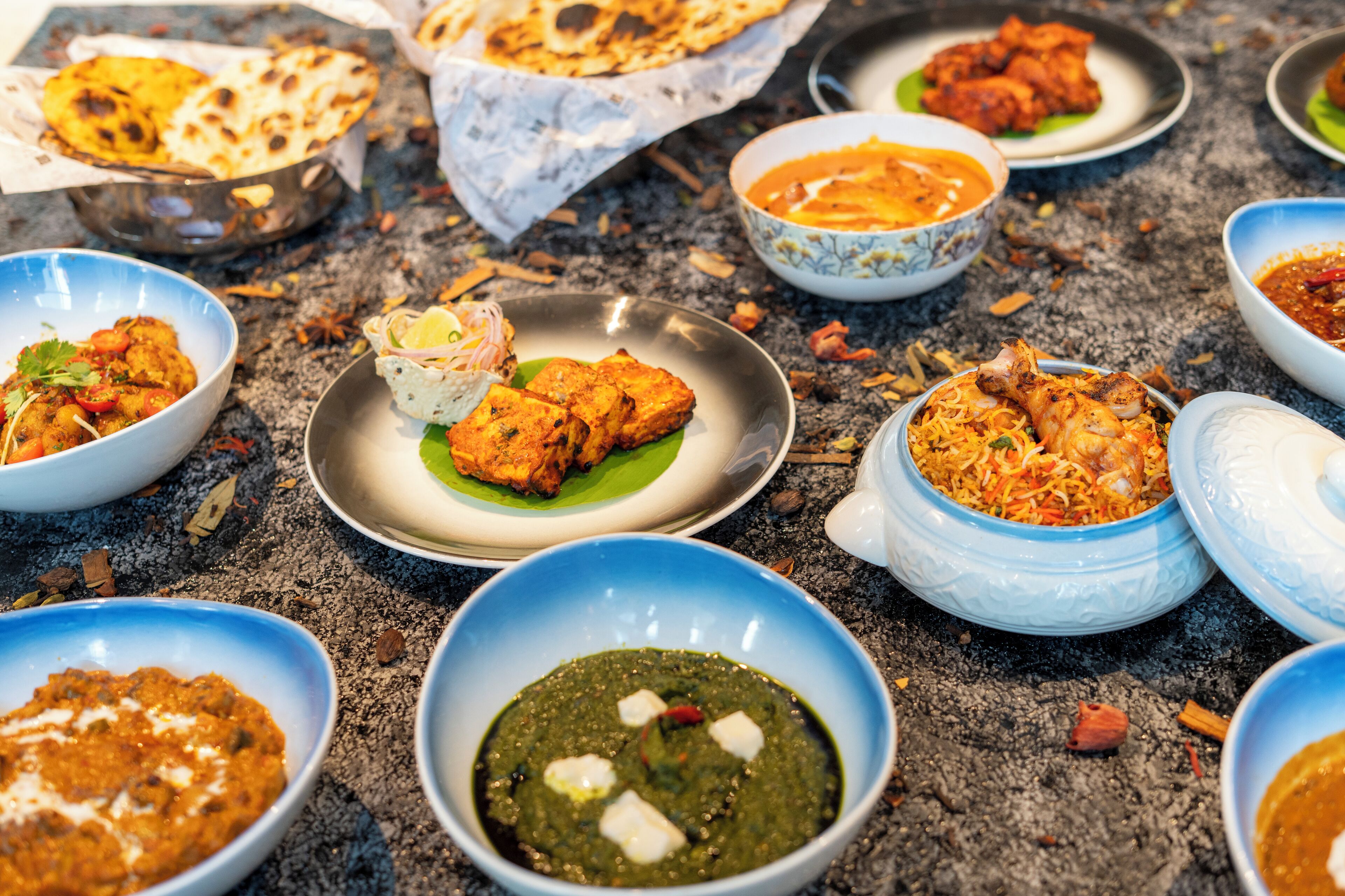 Verschiedene indische Gerichte, darunter Tandoori-Hähnchen, Paneer und ein grünes Chutney.