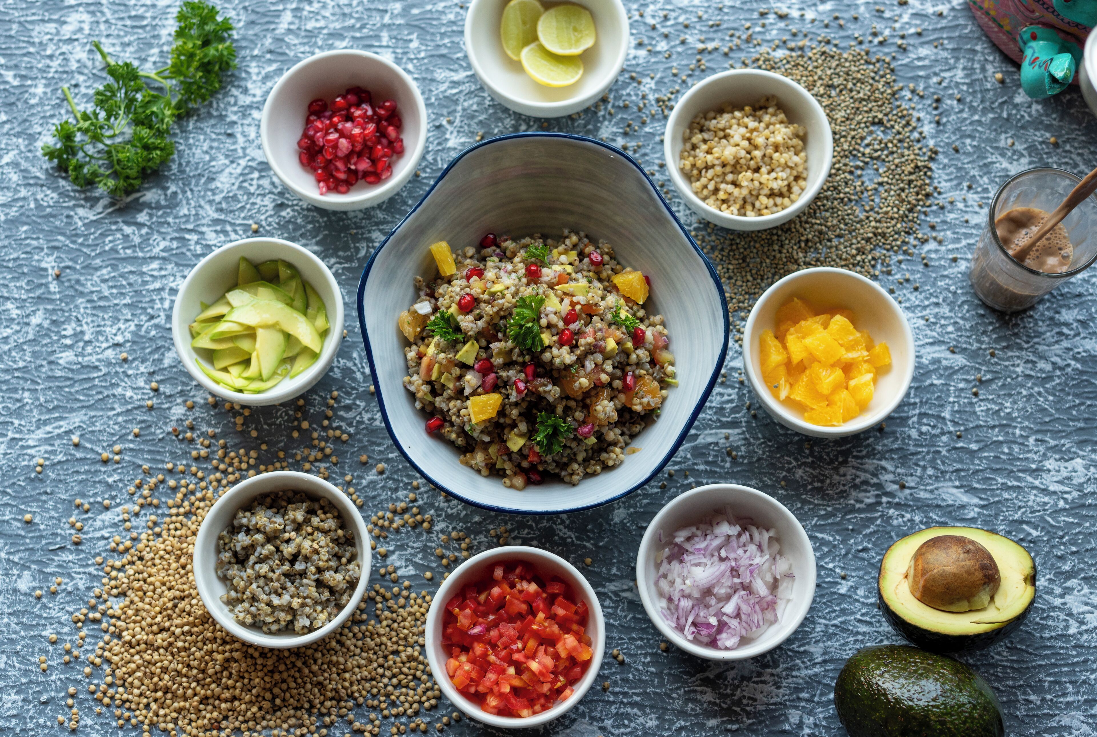 Een saladekom met diverse ingrediënten, omringd door kommen met fruit en groenten.