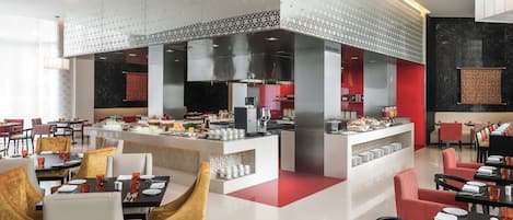 A modern restaurant with a central bar area, multiple seating options, and a visible kitchen.