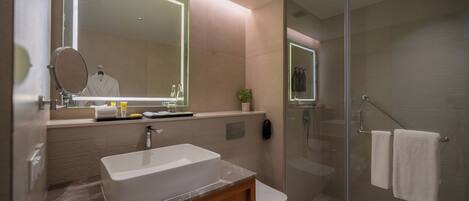 A modern bathroom with a large mirror, a sink, a toilet, and a glass-enclosed shower.