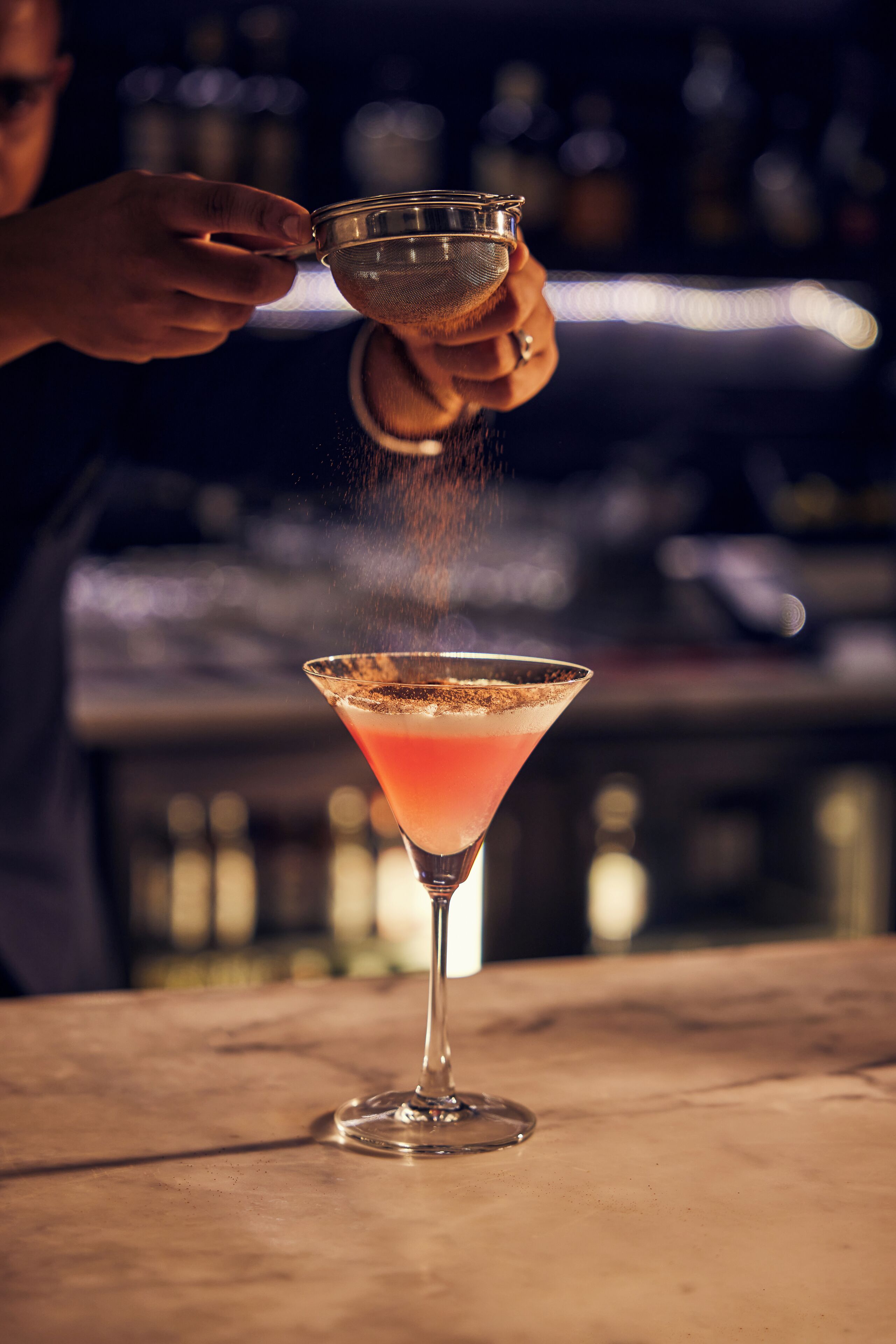 Una persona sirve una bebida en una copa de martini.