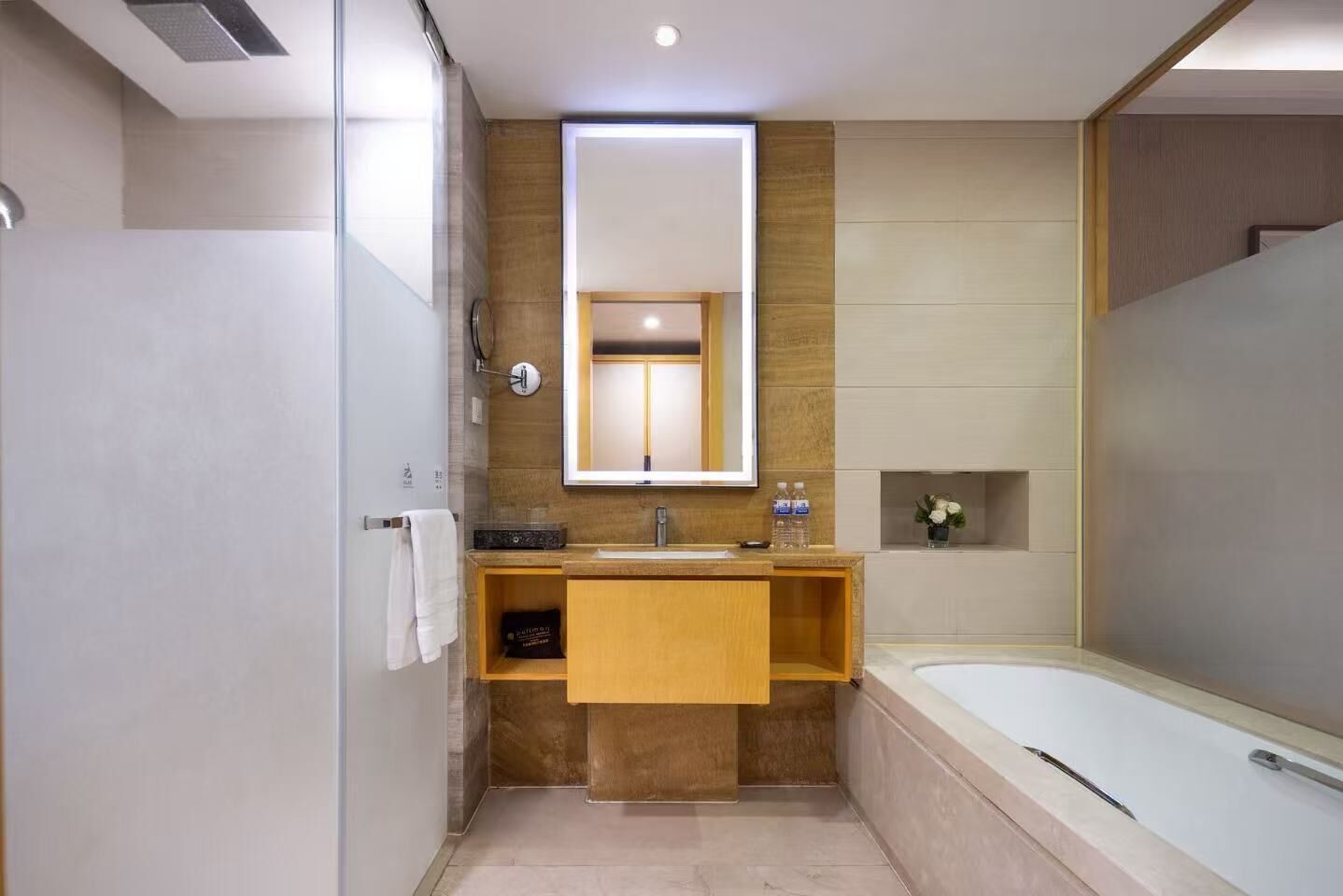 A modern bathroom with a wooden vanity, a large mirror, and a bathtub.