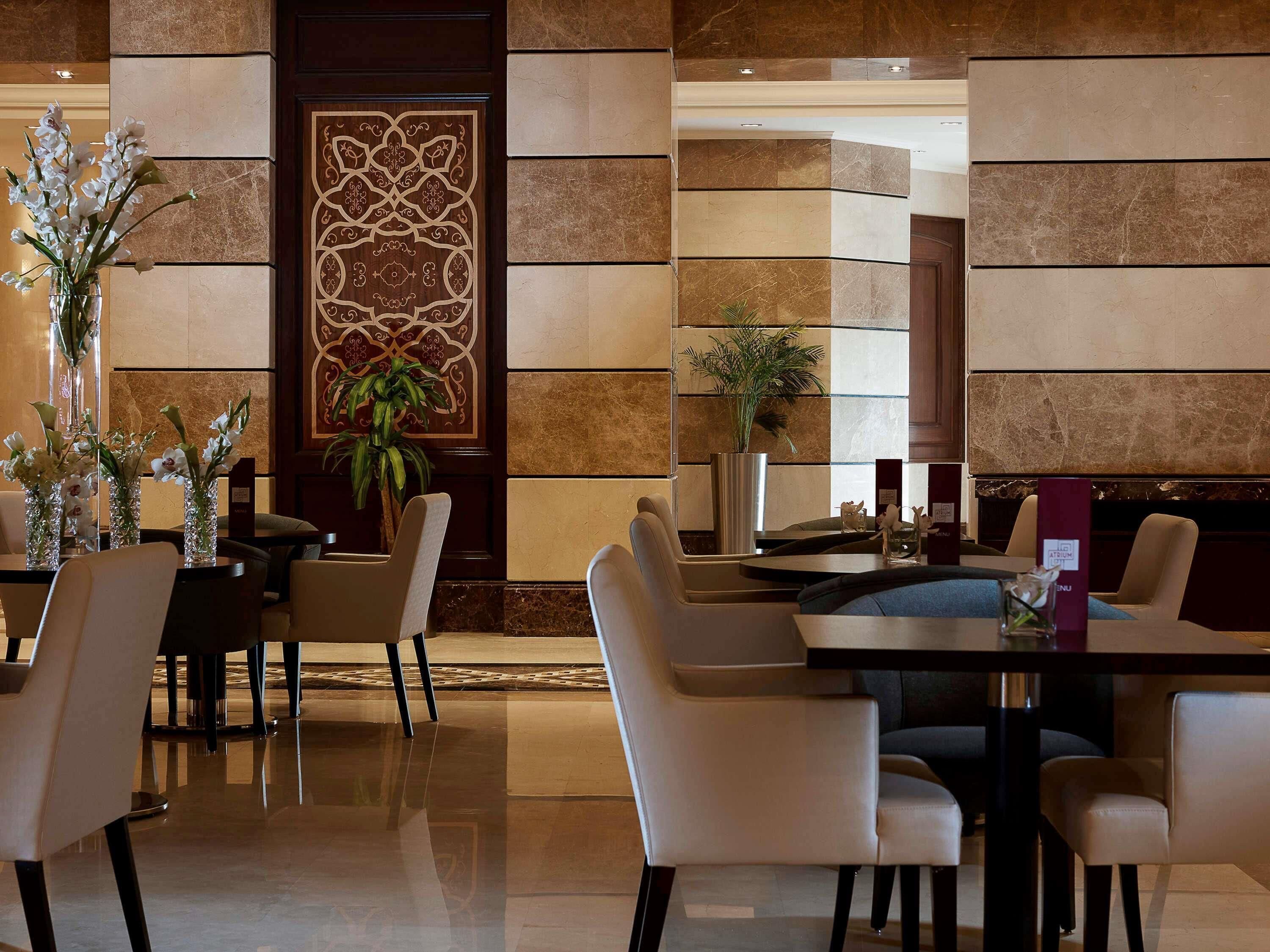 Een hotel lobby met een receptiebalie, een zithoek en decoratieve elementen zoals vazen en planten.