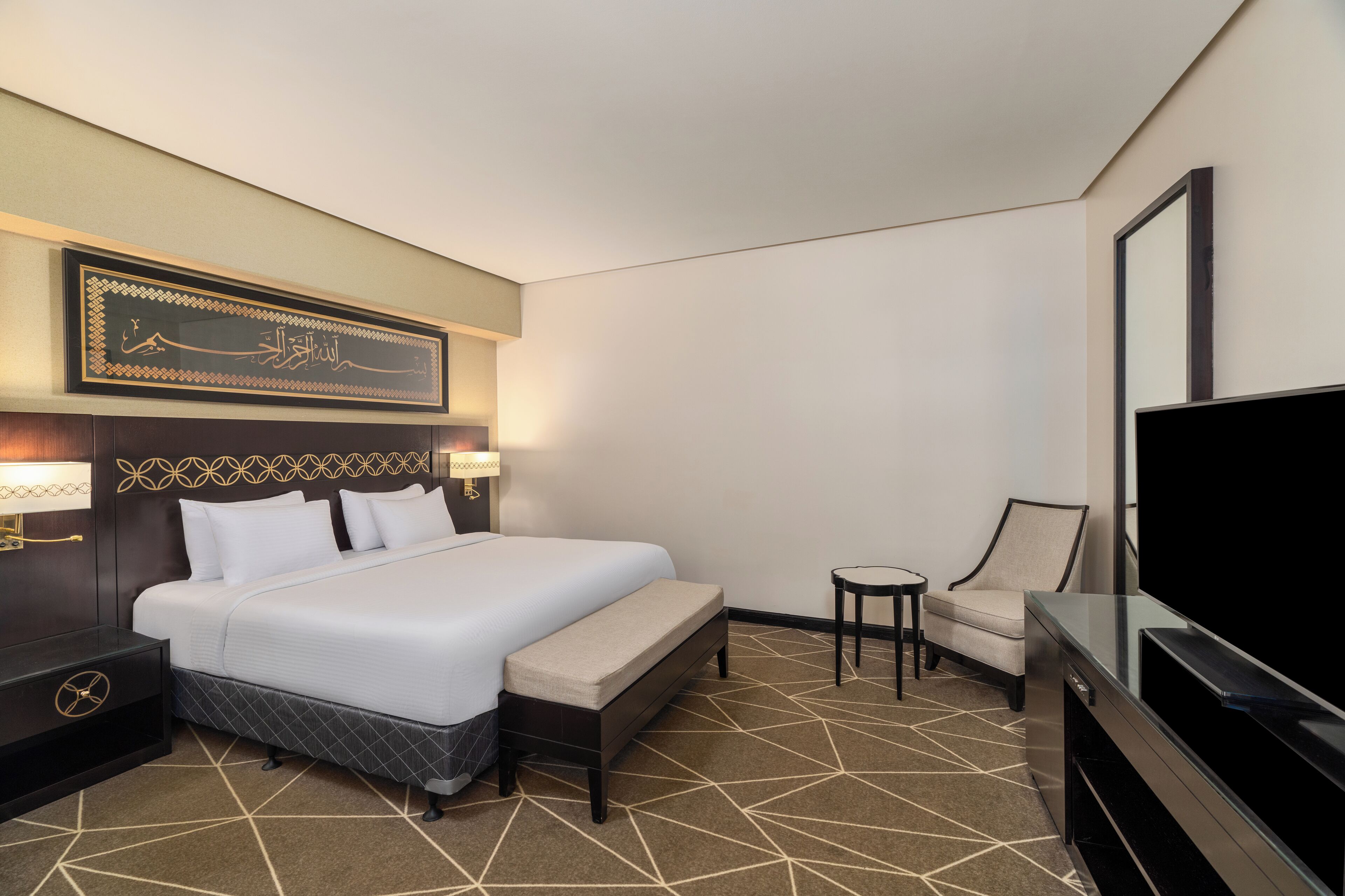 Une chambre d’hôtel avec un grand lit, une télévision, une chaise et une petite table.