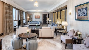 A spacious living area with a sofa set, ottomans, and a chandelier.