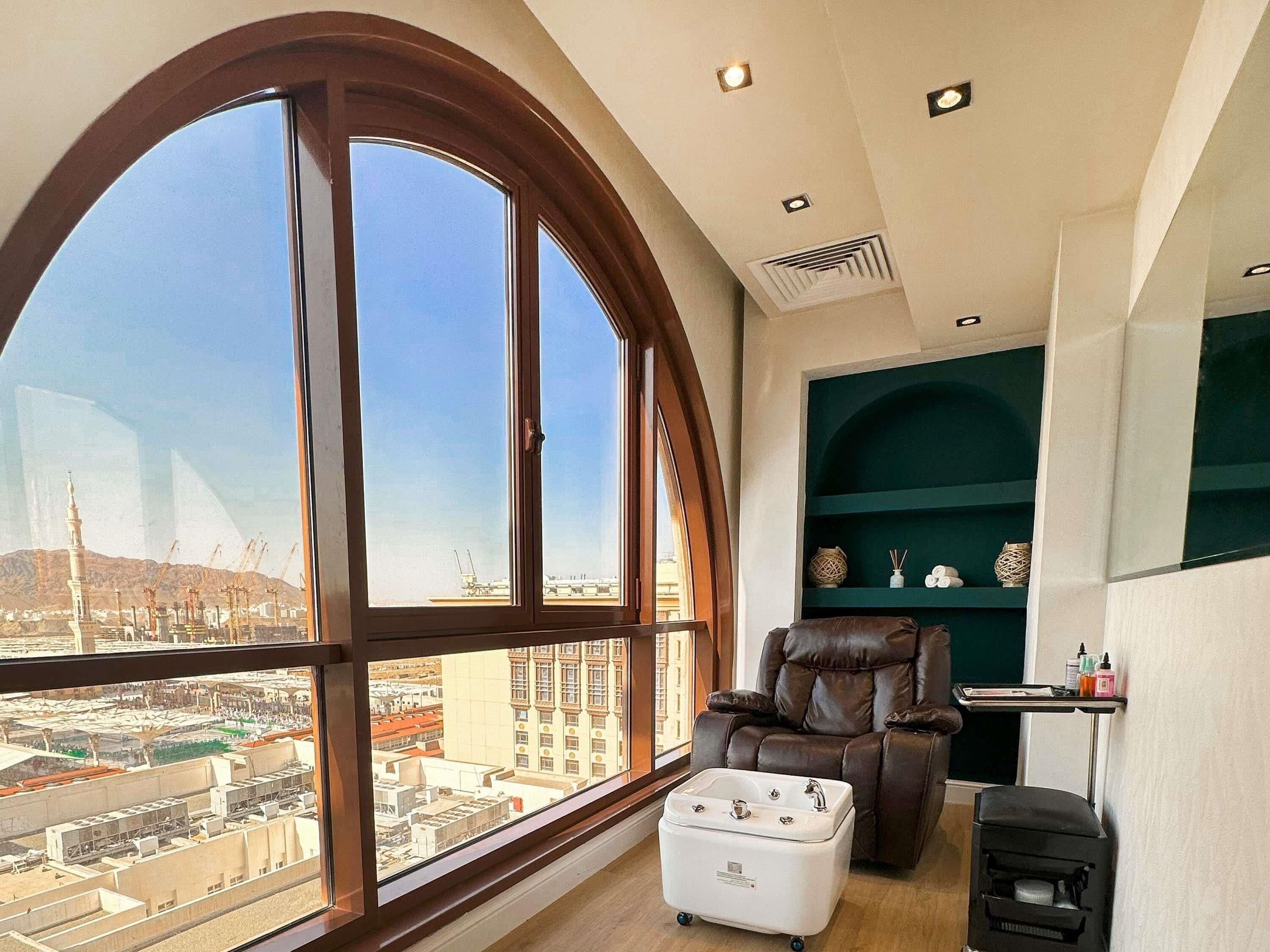 A room with a large arched window, a leather recliner, a white portable sink, and a small heater.