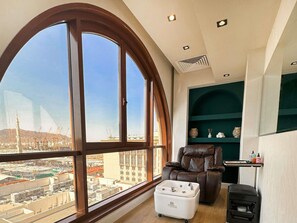 A room with a large arched window, a leather recliner, a white portable sink, and a small heater.