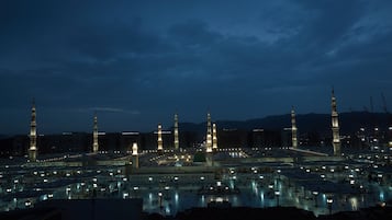 A large, illuminated mosque complex at night with multiple minarets and a vast open courtyard.