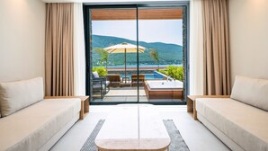 A modern room with a large sliding glass door leading to an outdoor area with a pool and a view of hills. - La Blanche Island Bodrum - All Inclusive (Milas)
