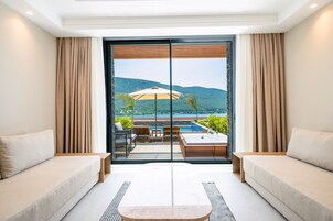 A modern room with a large sliding glass door leading to an outdoor area with a pool and a view of hills.