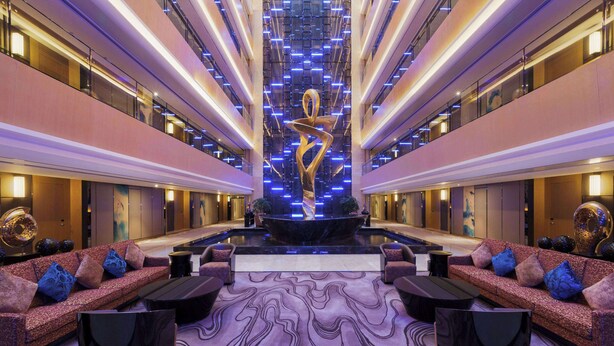 A spacious lobby with a central sculpture, multiple seating areas, and a patterned carpet. - Wyndham Chongqing Yuelai (Chongqing)