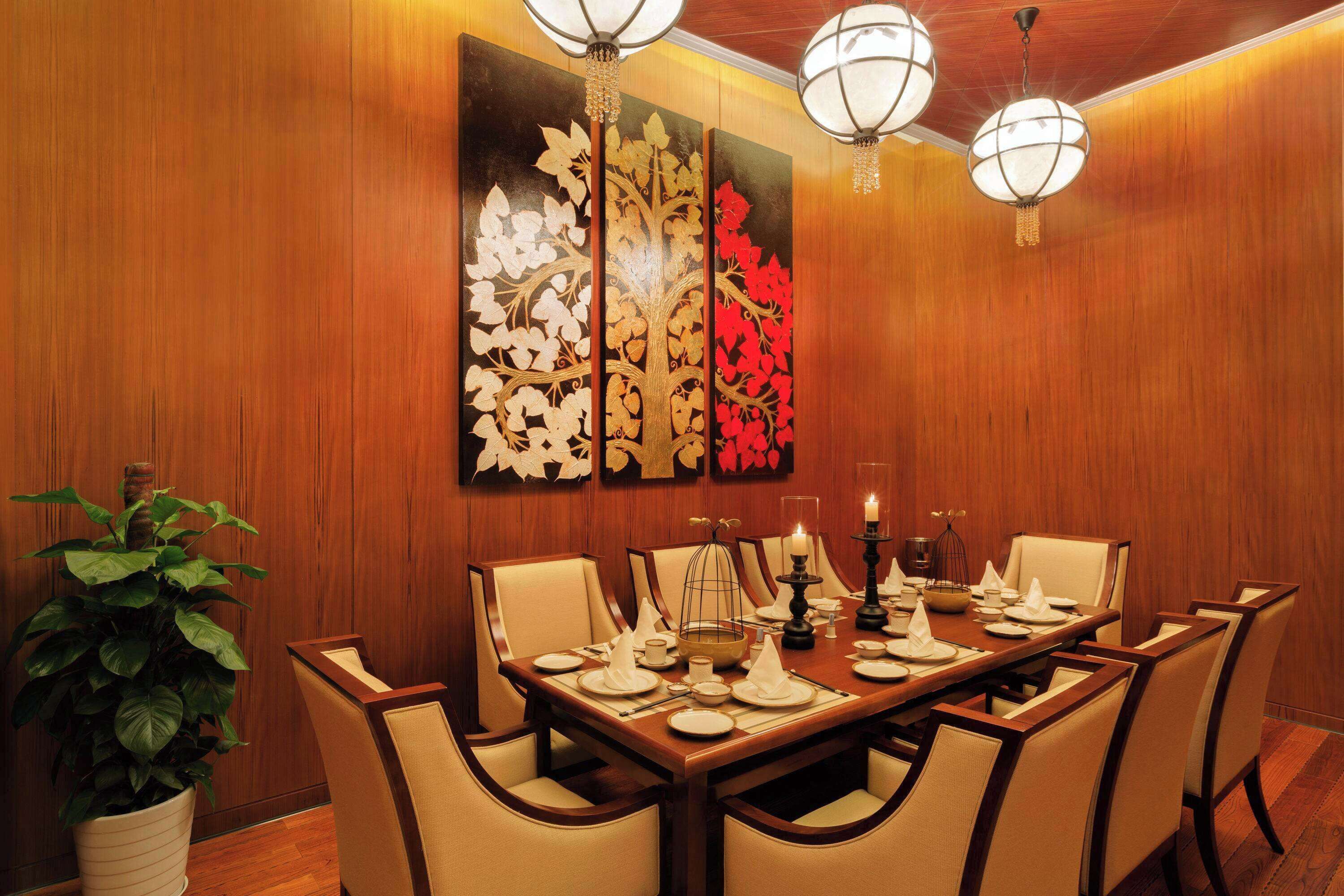 A dining area with a wooden wall, a large painting, and a chandelier.
