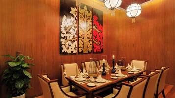 A dining area with a wooden wall, a large painting, and a chandelier.